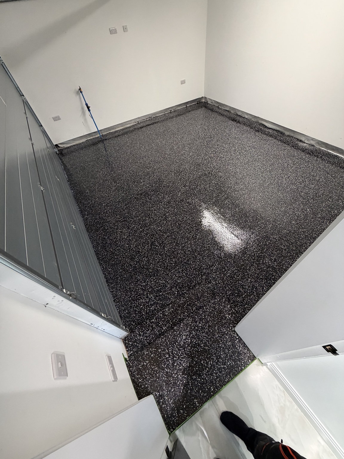 The same garage after Resique installed a black, grey and white decorative flake floor