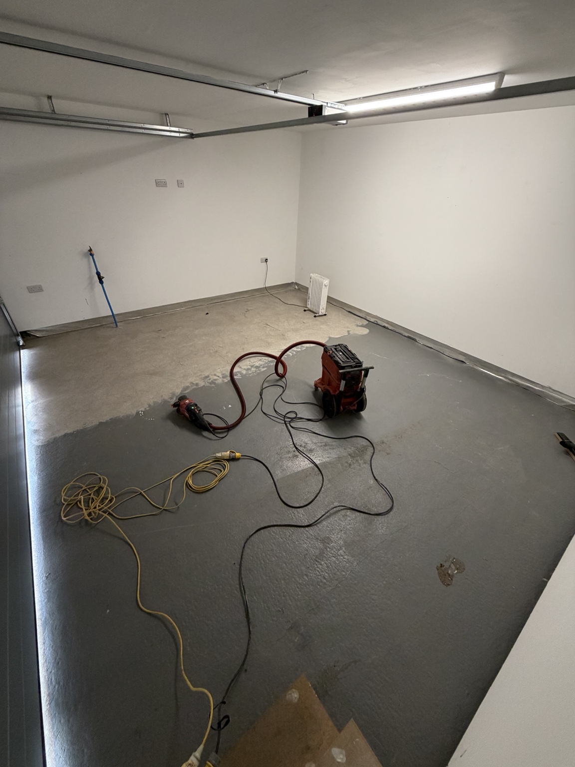 Resique garage project before completion, with worn grey coating and surface preparation underway